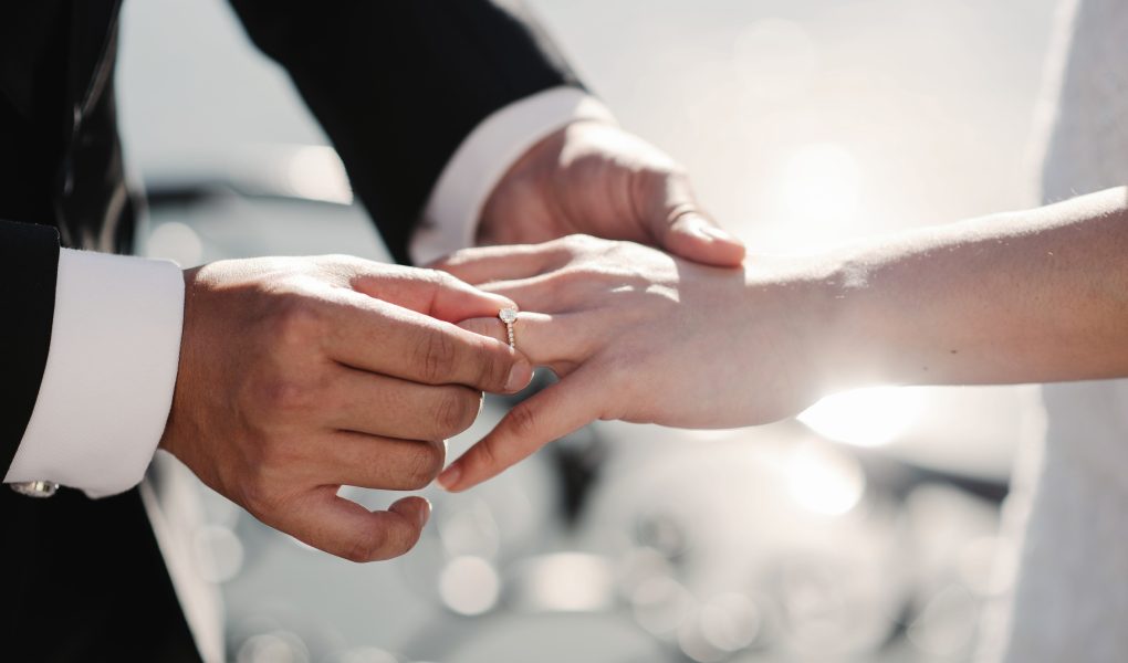 Mariée et marié tenant leurs alliances dorées lors du mariage civil, illustration du coût du mariage civil en Belgique