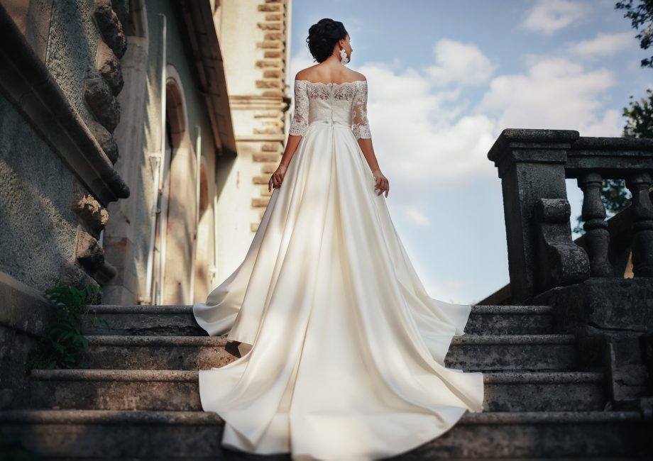 Robe de mariée 2027 : mariée élégante en robe de créateur devant un château médiéval
